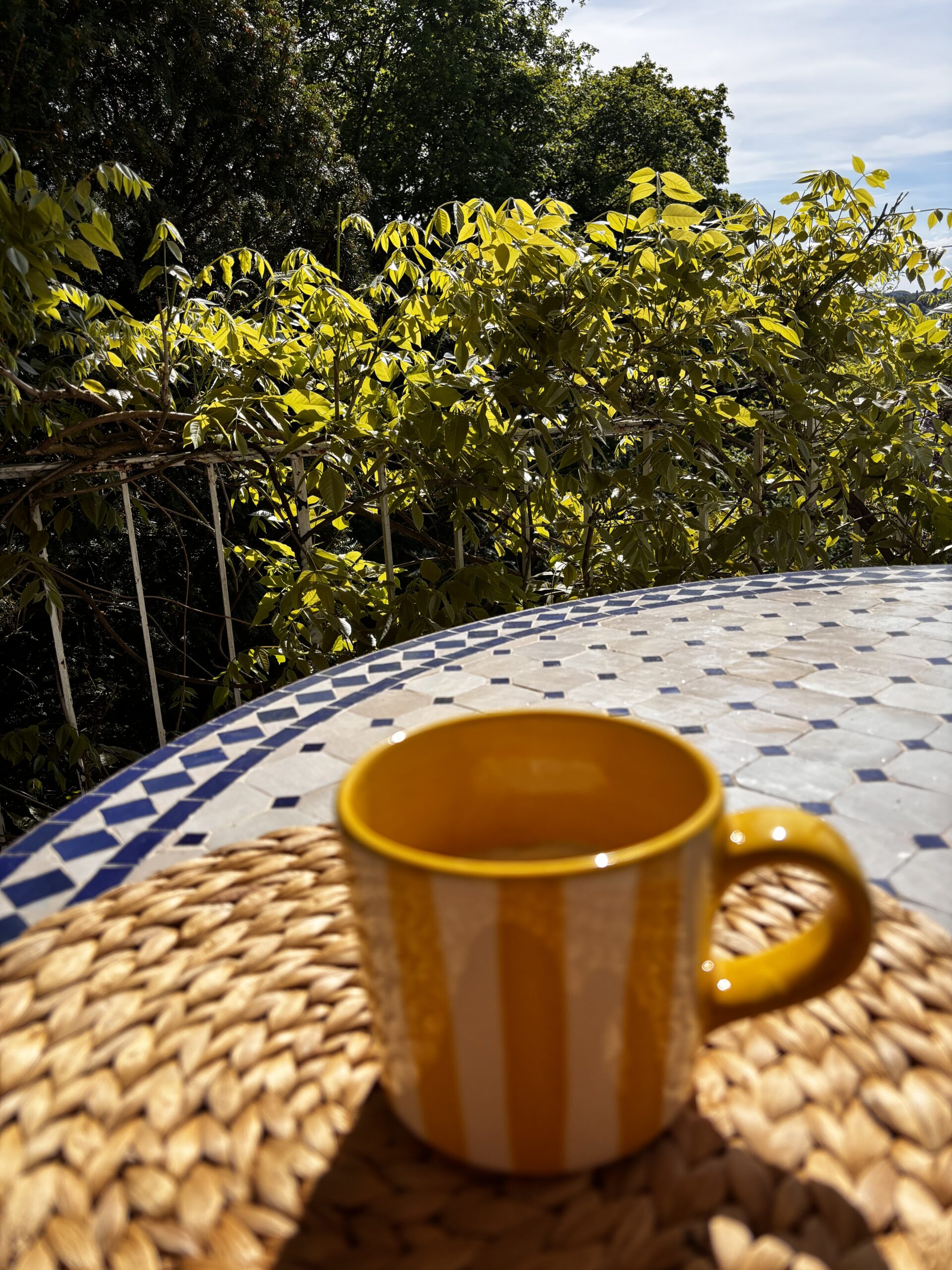 eine gelbe Tasse steht auf dem tisch vor blauem frühlingshimmel
